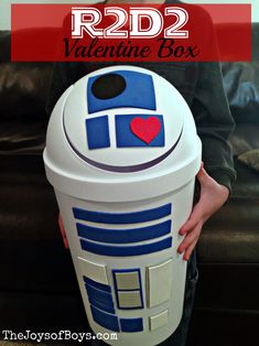 a boy holding a r2d2 valentine box with the words, r2d2 valentine box