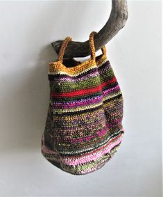 a handbag hanging on a wall with a wooden branch