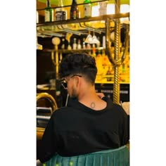 a man sitting in a green chair with his back turned to the camera, wearing sunglasses and a black t - shirt