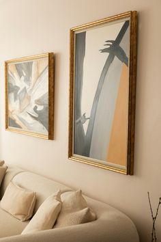 two paintings hang on the wall above a couch