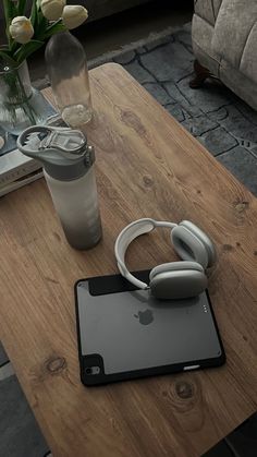 an ipad and headphones are sitting on a coffee table next to a vase with tulips