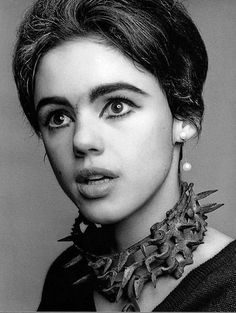 a black and white photo of a woman with large earrings on her neck looking at the camera