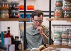 a man standing in front of shelves with food on it and looking at his cell phone