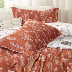 an orange and white comforter with flowers on it