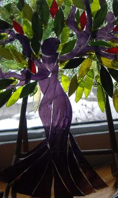 a purple vase sitting on top of a window sill filled with flowers and leaves