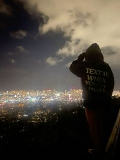 a person standing on top of a hill looking at the city lights in the distance