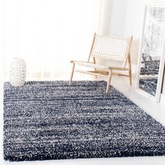 a white chair sitting in front of a window next to a blue rug on top of a hard wood floor