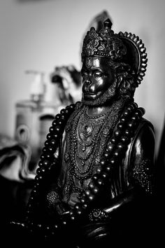 a black and white photo of a buddha statue with beads on it's head