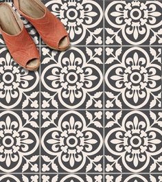 two pairs of shoes sitting on top of a black and white tile floor