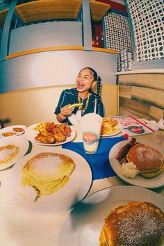 a woman sitting at a table with plates of food