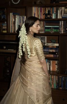 a woman standing in front of a bookshelf wearing a gold dress and veil