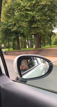 the side view mirror of a car with trees in the background