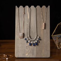 the necklaces are on display in front of a wooden stand with other jewelry items