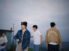 three young men standing next to each other on top of a hill looking at the sky