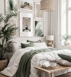 a bed with white sheets and green pillows in a room filled with pictures on the wall