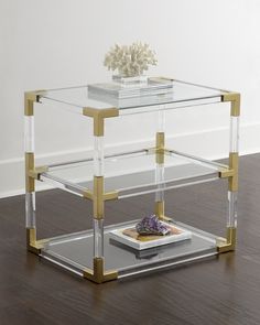 a glass and gold end table with a flower on top in a living room setting