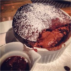 a dessert with powdered sugar on top and sauce in small dishes next to it