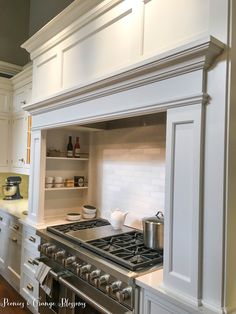 a stove top oven sitting inside of a kitchen next to white cupboards and drawers