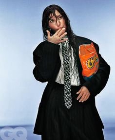 a man in a suit and tie is holding an orange boxing glove over his mouth