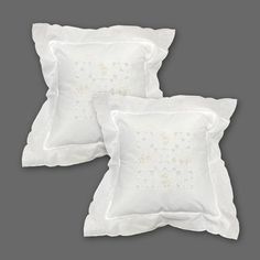 three white pillows with embroidered flowers on the front and back, one is made out of linen