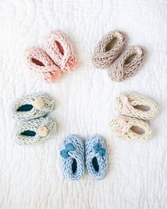 crocheted baby shoes and slippers laid out on a bed