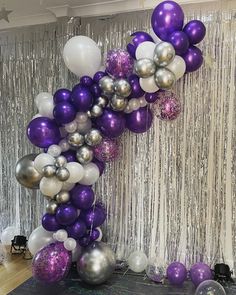 purple and silver balloons are hanging from the ceiling