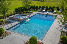 an aerial view of a swimming pool surrounded by greenery and trees with lounge chairs around it