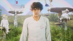 a young man standing in front of an array of fake mushrooms and other strange objects