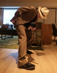 a man in a suit and hat taking a photo with a camera on the floor