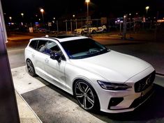 a white car is parked on the street at night