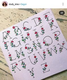 a sticker with the letters and flowers on it is sitting on top of a piece of paper