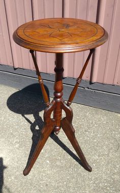 a small wooden table sitting in front of a pink building