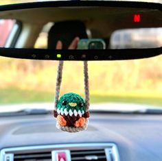 a small stuffed bird hanging from a car's rearview mirror holder in the passenger seat