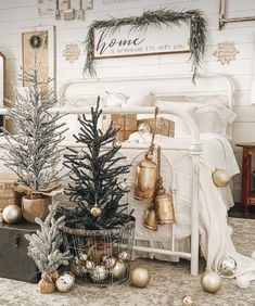 a christmas tree in a basket next to a bed with white sheets and gold ornaments