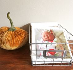 a small pumpkin sitting on top of a wooden table next to a cell phone holder