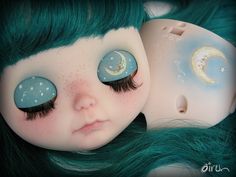 a doll with green hair laying on top of it's head next to another doll