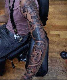 a man with a clock tattoo on his arm sitting in front of a computer desk