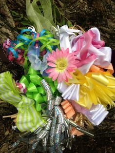 a bouquet of colorful flowers sitting on top of a grass covered ground next to a tree