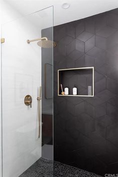 a bathroom with hexagonal tiles on the wall and gold fixtures in the shower