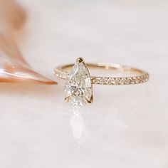 a diamond ring sitting on top of a white table next to a seashell and shell