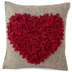 a heart made out of red flowers on a gray pillow