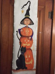 a halloween door hanger with a black cat and pumpkins