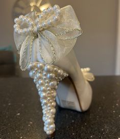 a pair of white shoes with pearls on them