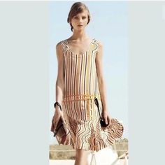 a woman in a dress is standing on the beach with her handbag and purse