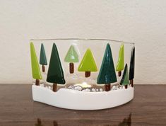 a glass bowl with trees in it sitting on a table