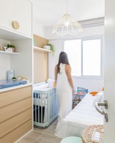 a woman in a white dress standing next to a baby crib