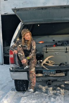 a woman is sitting in the back of a truck with deer antlers on it