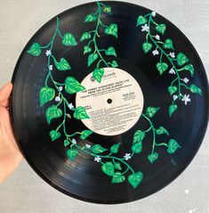 a hand holding a black record with green leaves on it