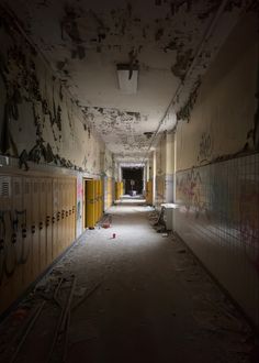 an empty hallway with lockers and graffiti all over the walls on either side of it