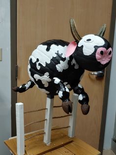 a fake cow sitting on top of a wooden table